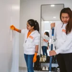 Kuvassa kaksi henkilöä tekee kotisiivousta.